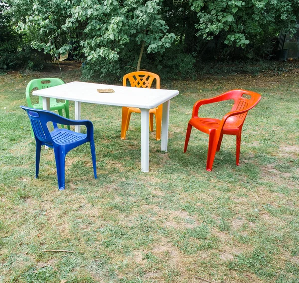 Kunststofftisch und vier Stühle draußen auf Gras. — Stockfoto