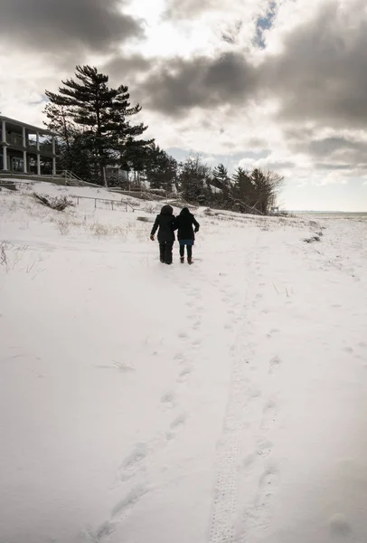 Dos personas caminando cuesta arriba, en un paisaje cubierto de nieve — Foto de Stock