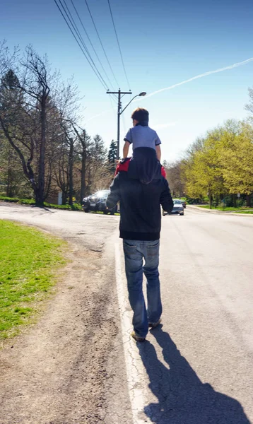 Hombre caminando por el camino llevando chico — Foto de Stock