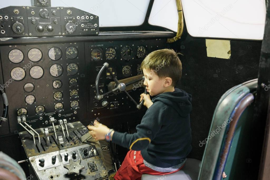 Young boy in cockpit of stationary aeroplane