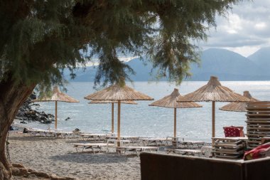 Thatched beach kanopiler ve dağda Nikos Agiolaos, Crete, Yunanistan