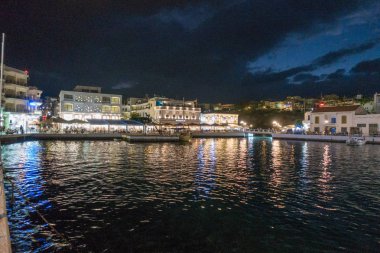 Deniz manzarası ve aydınlatılmış binalar gece Nikos Agiolaos, Crete, Yunanistan