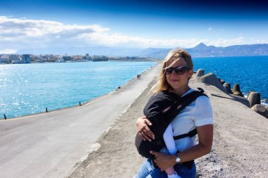 Anne ile bebek iskelesi ile deniz ve uzak dağ üzerinde Heraklion, Yunanistan