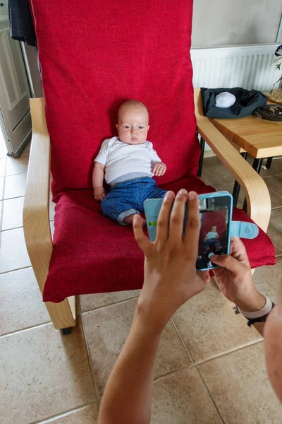 Mother Photographing Her Baby Boy Sitting Armchair Using Mobile Camera — Stock Photo, Image