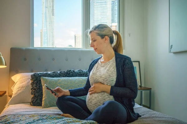 Mujer Tocando Vientre Embarazada Mensajería Usando Teléfono Cama —  Fotos de Stock