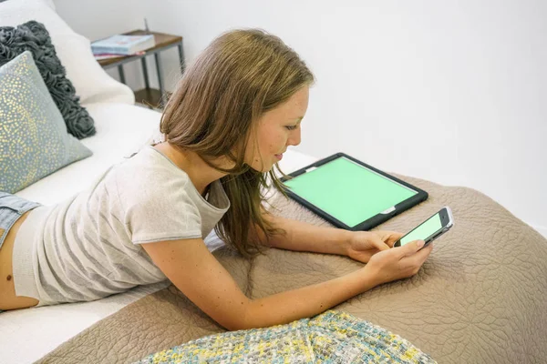 若い女性のソーシャルネットワー キングのベッドで彼女の携帯電話で — ストック写真