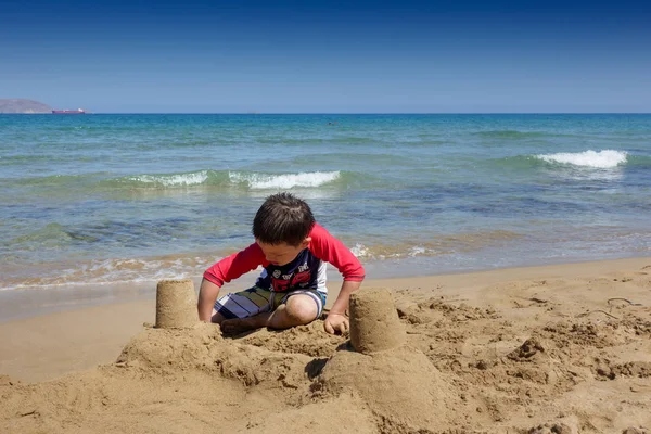 小男孩建筑沙子城堡在海滩 克里特岛 — 图库照片