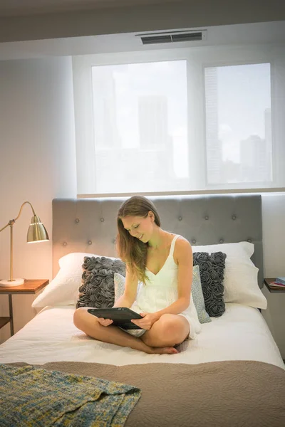 ナイトウェア デジタル タブレットを使用してベッドの中で幸せな若い女 — ストック写真