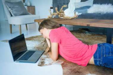 Endişeli genç kadın evde yerde yatarken sırasında dizüstü bilgisayar kullanarak