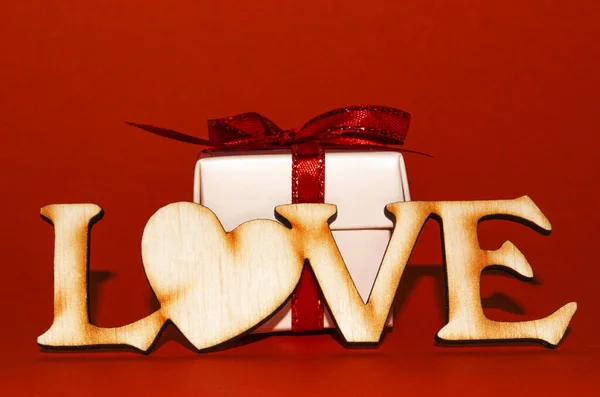 word love made of wooden letters and gift on a red background