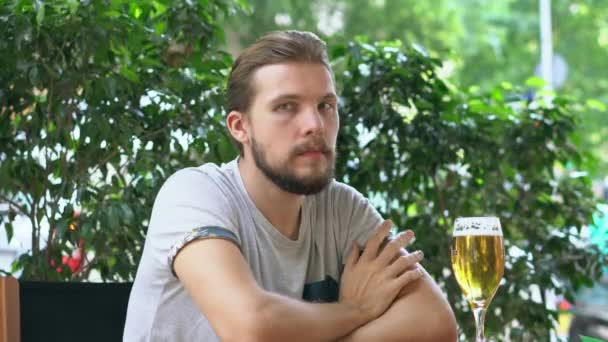 Молодой человек пьет пиво на открытом воздухе — стоковое видео