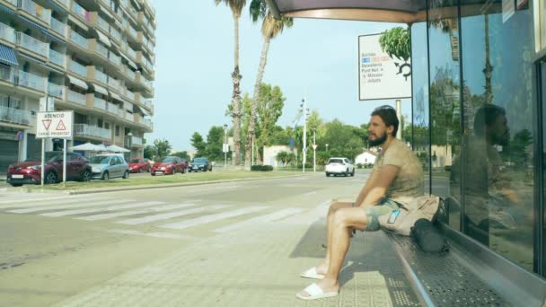 Jonge man wachtend op een bus — Stockvideo