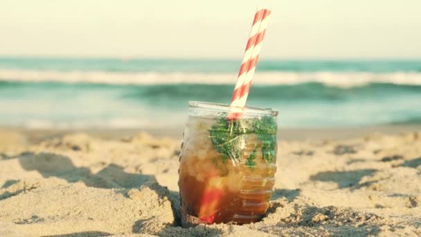 Misted vaso de bebida en la arena en la playa — Vídeos de Stock