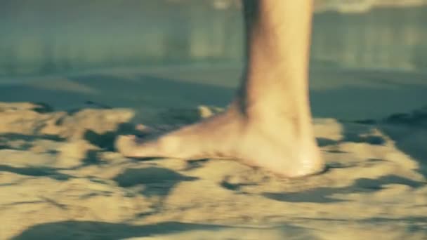 Мужские ноги прогуливаясь по пляжу и подобрать банку напитка — стоковое видео