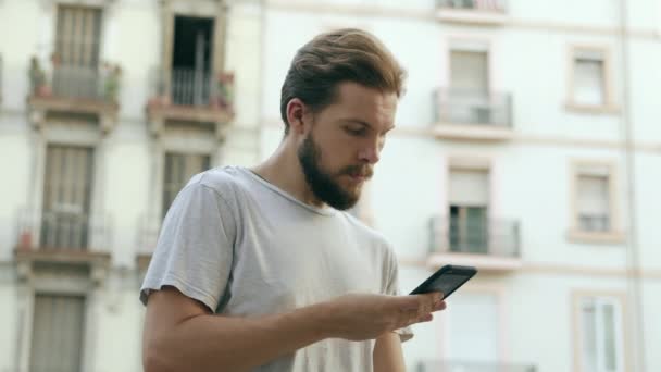 Unge man kollar smarttelefon utomhus — Stockvideo