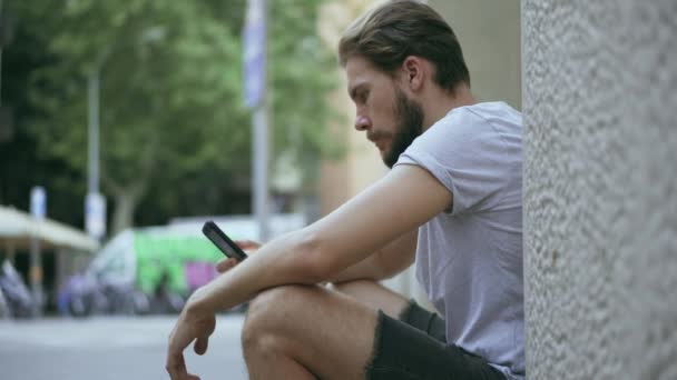 Unge man kollar smarttelefon utomhus — Stockvideo