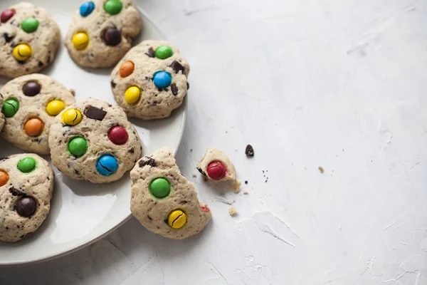 Galletas de chocolate chip americano y dulces de colores en un plato sobre un fondo gris. Para calendario, libro de cocina, recetas, tarjetas . — Foto de Stock