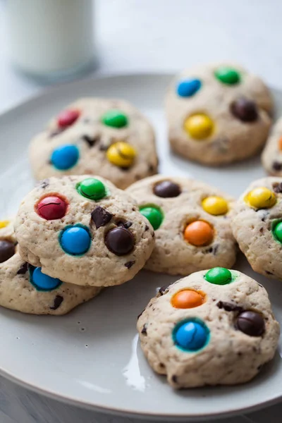 Chocoladechip Amerikaanse koekjes en gekleurde snoepjes op een bord op een grijze achtergrond. Voor agenda, kookboek, recepten, kaarten. — Stockfoto