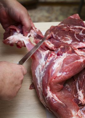 Beyaz tahtada taze domuz eti kesen bir adam.
