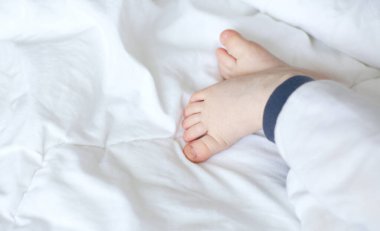 Beyaz arka planda uyuyan bir bebeğin bacakları. Bir çocuğun hayali.