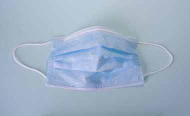 Mavi maske mavi arka planda, koronavirüse karşı bireysel koruma.