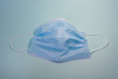 Mavi maske mavi arka planda, koronavirüse karşı bireysel koruma.