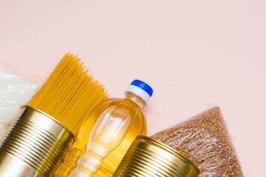 Gıda stokları, pembe bir arka planda karantina süresi boyunca yiyecek stokları krizine girer. Makarna, konserve yemek, tereyağı, şeker, karabuğday. Yiyecek teslimatı, bağış, koronavirüs karantinası..