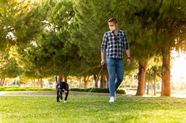 Korumalı maske takan bir adam, Corona virüsü salgını yüzünden dışarıda köpekle tek başına yürüyor.