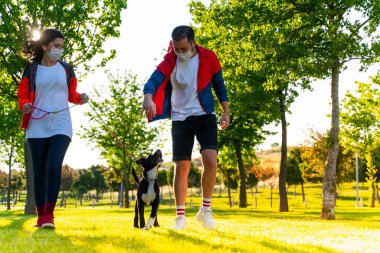 Korumalı maske takan genç bir çift, Corona virüsü salgını yüzünden dışarıda köpekle birlikte yürüyorlar.