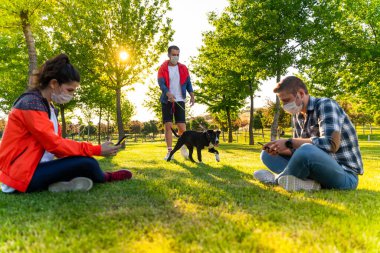 Korunaklı maske takan genç insanlar, Corona virüsü salgını yüzünden dışarıda köpekle birlikte yürüyorlar.