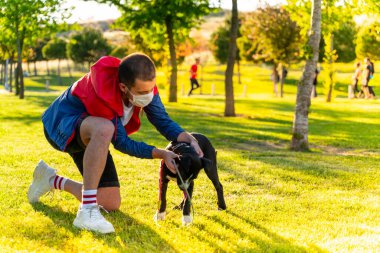 Korumalı maske takan bir adam, Corona virüsü salgını yüzünden dışarıda köpekle tek başına yürüyor.