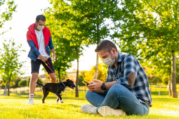 young people wearing a protective mask is walking alone with a dog outdoors because of the corona virus pandemic covid-19