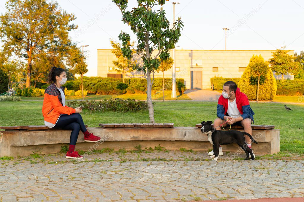 A young lovers couple sits in a spring park with their dog
