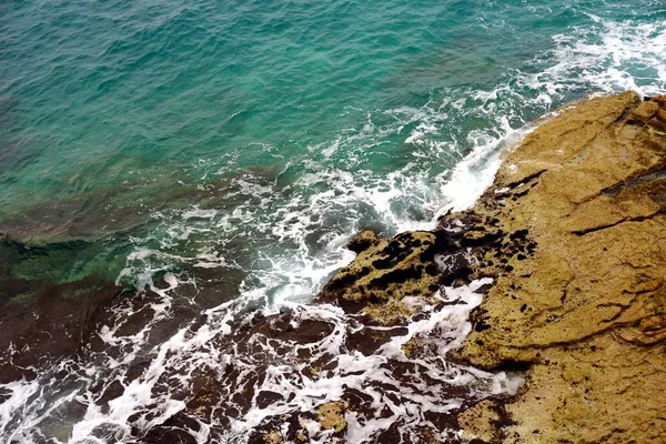Mar profundo con espuma de mar en la superficie y olas que chocan en la costa rocosa — Foto de Stock