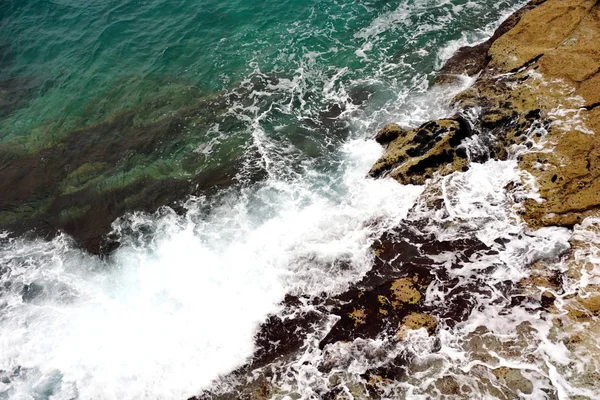 Superficie de mar turquesa y espuma de mar blanca y olas que salpica la piedra en la costa — Foto de Stock