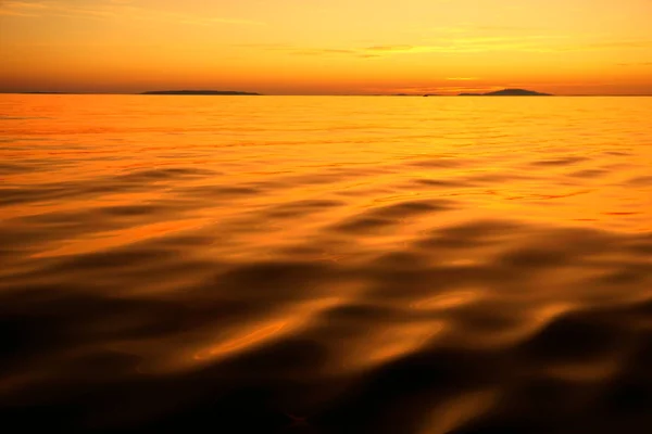 Cor laranja vívida por do sol com superfície de água colorida irreal e céu. Fundo abstrato da natureza com cor como em um planeta desconhecido — Fotografia de Stock