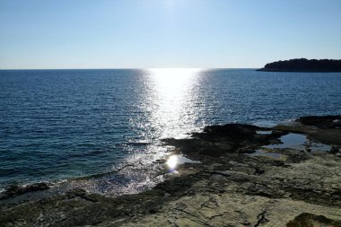 Mavi deniz yüzeyinde parıldayan ışık izleri. Güneş ışığı deniz suyundan ve küçük dalgalardan yansıdığında.