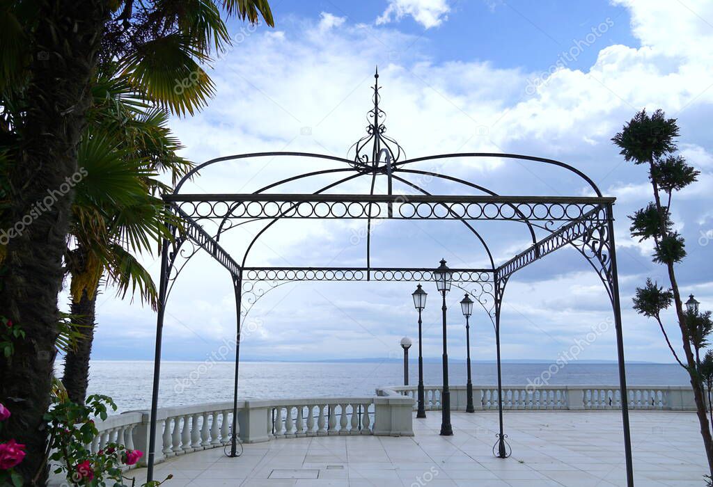 Empty promenade and view to the sea and cloudy sky through the gazebo