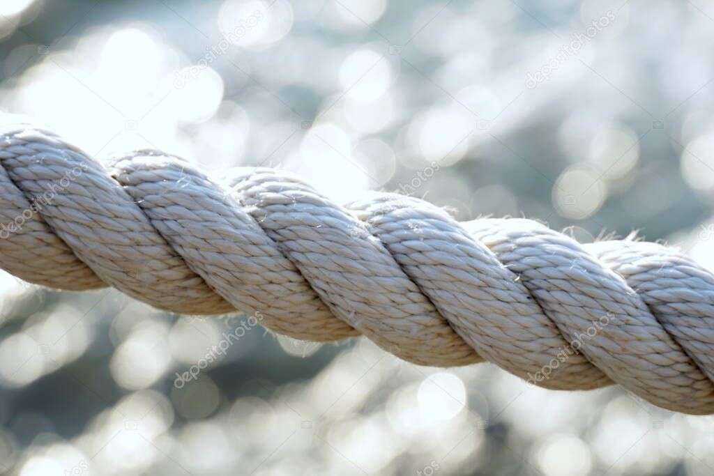 Close up view of twisted marine cotton cord laid diagonally in front of blurred sea