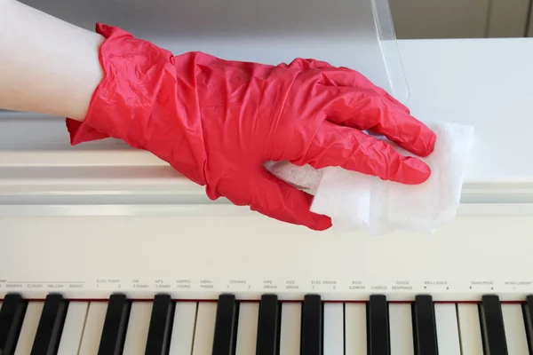 Coronavirus COVID-19 sanitize disinfecting wipes cleaning disinfection of musical instrument. Wiping with antibacterial wipe the surface of piano and keyboard, at room against corona virus COVID-19.