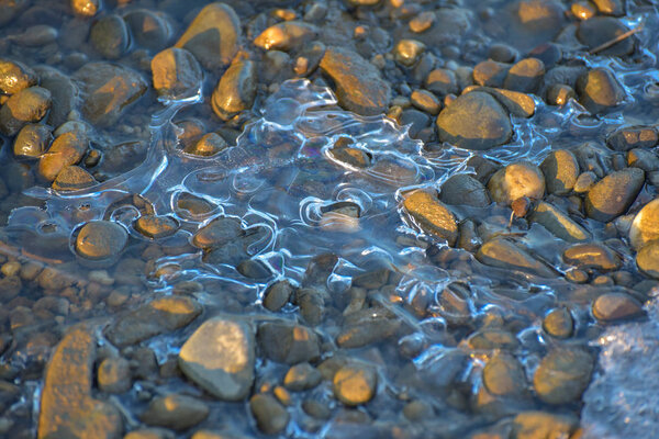 The play of the light of the sun, ice and water on a mountain river
