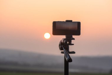 Akıllı telefon dağlarda gün batımını bekliyor.