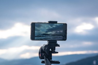 Akıllı telefon dağlarda gün batımını bekliyor.