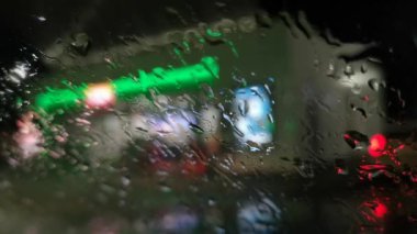 Gece şehrinin manzaraları Yağmurun altında ön camdan