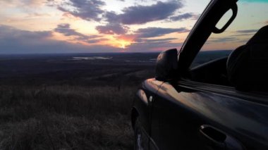 SUV sürücüsü gün batımında çay içer.