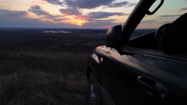SUV sürücüsü gün batımında çay içer.