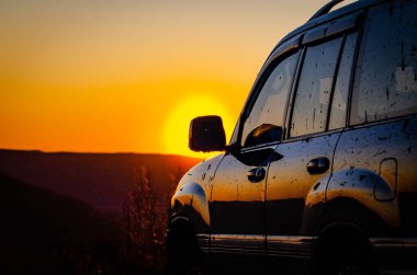 SUV, Karpatlar 'la gün batımında seyahat ediyor.