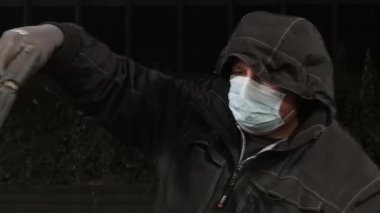 Tıbbi maskeli bir adam araba yıkar.