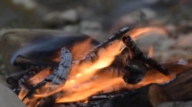 Şiddetli bir rüzgarla nehir kıyısında kamp ateşi