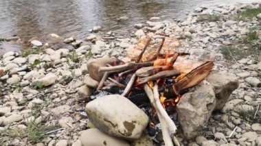 Şiddetli bir rüzgarla nehir kıyısında kamp ateşi